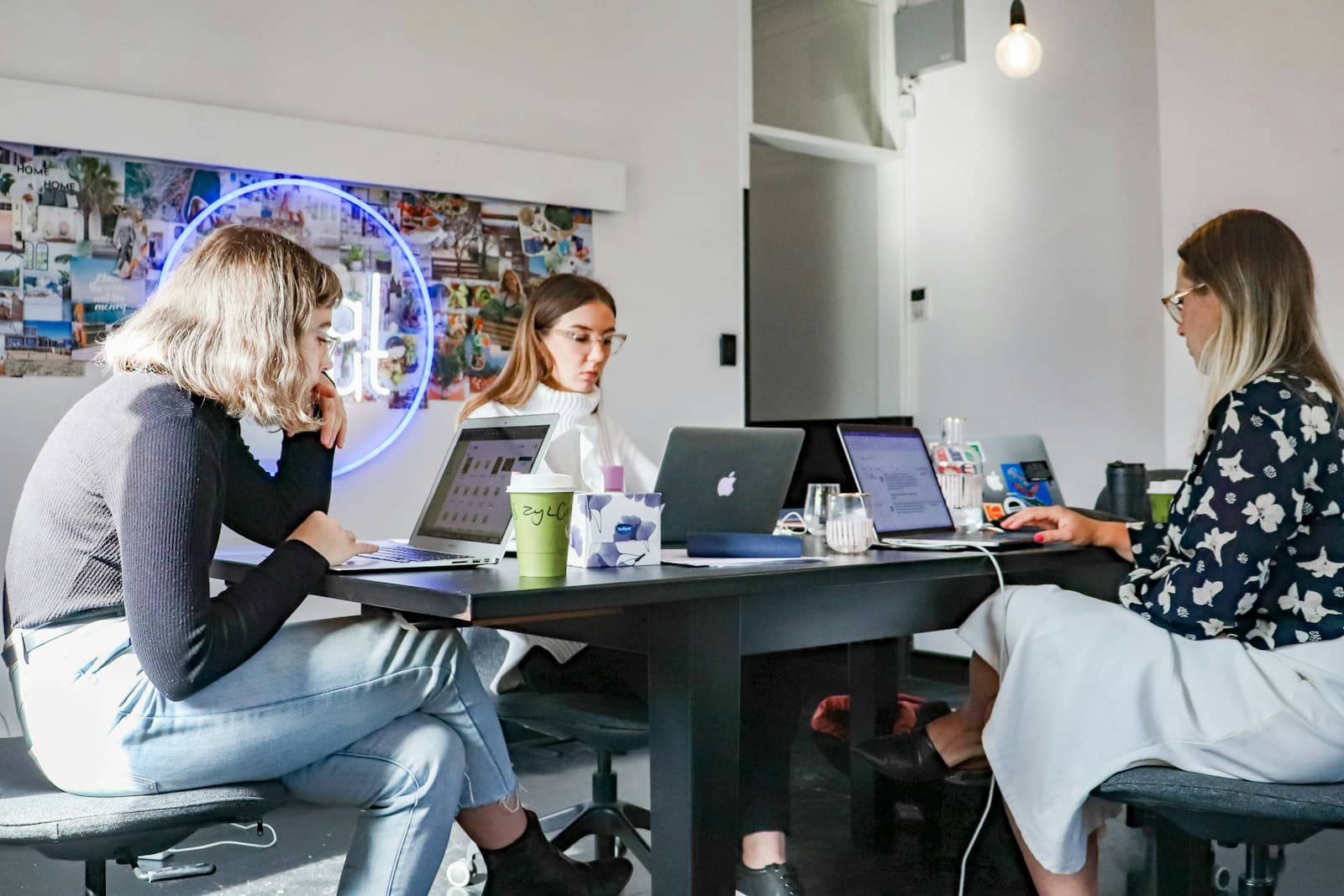 Three engineers collaborating with laptops at a modern workspace